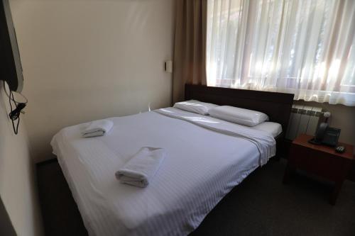 a bedroom with a white bed with towels on it at Hotel Happy in Dimitrovgrad