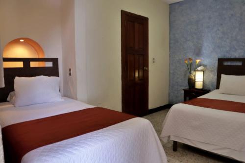 a hotel room with two beds and a door at Hotel Posada San Miguel in Antigua Guatemala