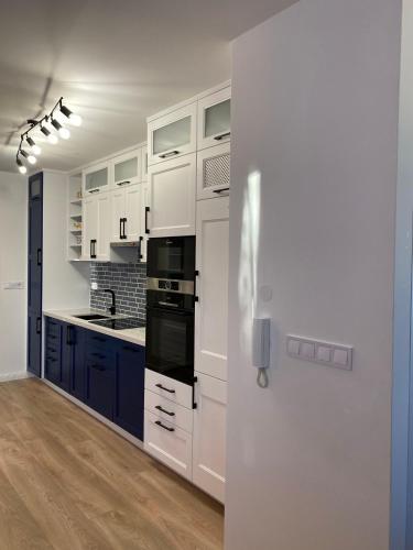 a white kitchen with blue cabinets and a refrigerator at Moonshine Érd in Érd