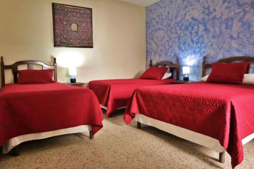 2 Betten in einem Zimmer mit roten Decken in der Unterkunft Hotel Posada San Miguel in Antigua Guatemala