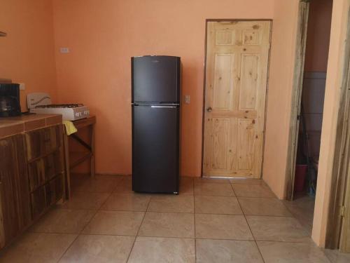 a black refrigerator in a kitchen with a door at Casa del Eucalipto in Sabana Redonda