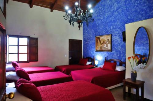 a room with three beds and a chandelier at Hotel Posada San Miguel in Antigua Guatemala
