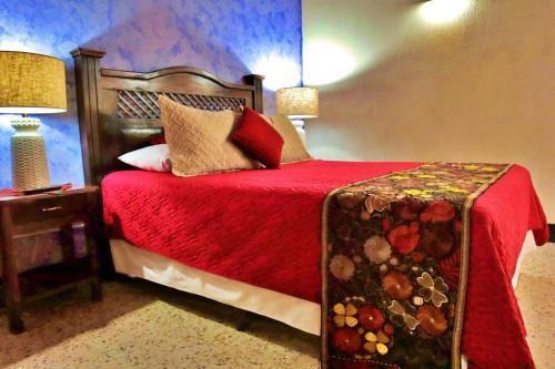 a bedroom with a bed with a red comforter at Hotel Posada San Miguel in Antigua Guatemala