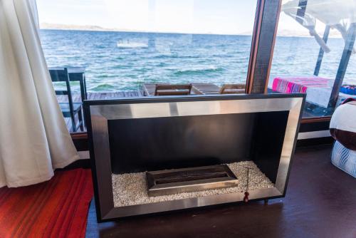 a fireplace in a room with a view of the ocean at Uros Titicaca Lodge in Puno