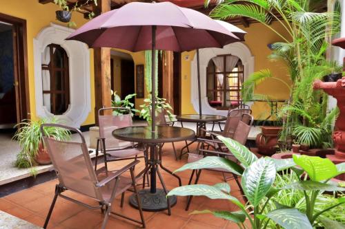 a patio with tables and chairs and an umbrella at Hotel Posada San Miguel in Antigua Guatemala