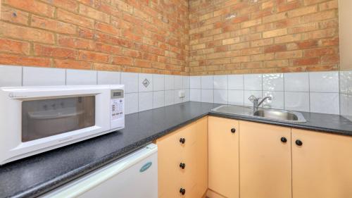 a kitchen with a microwave and a sink at Bridges on Meninya Motel & Apartments in Moama