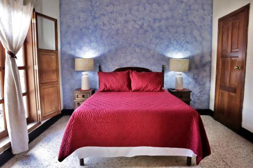 a bedroom with a red bed with two lamps and a window at Hotel Posada San Miguel in Antigua Guatemala