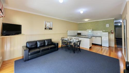 a living room with a couch and a table and a kitchen at Bridges on Meninya Motel & Apartments in Moama