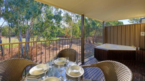 a table and chairs on a balcony with a tub at Bridges on Meninya Motel & Apartments in Moama
