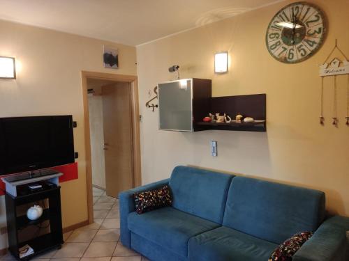 een woonkamer met een blauwe bank en een klok aan de muur bij Residenza tra Parma e Fiere in Baganzola