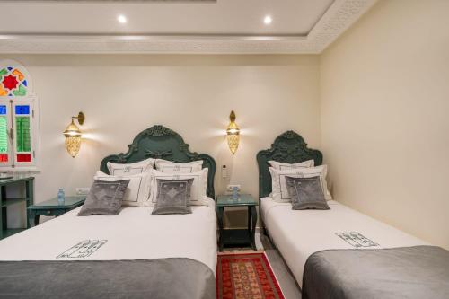 two twin beds in a room with two tables at HOTEL RIAD CHAMI in Marrakesh