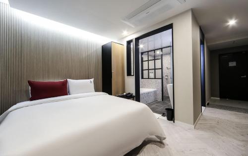 a bedroom with a large white bed and a bathroom at Maron Hotel Nampo in Busan