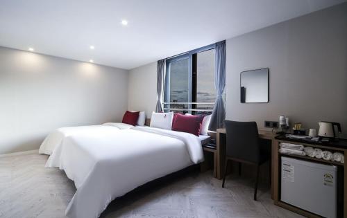 Maron Hotel Nampo في بوسان: غرفة في الفندق مع سرير أبيض كبير ومكتب