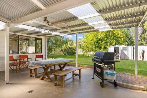 a patio with a picnic table and a grill at Abbey Beach Shack in Busselton