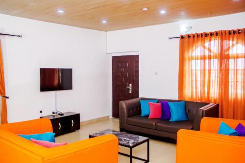 ein Wohnzimmer mit einem Sofa und 2 Stühlen in der Unterkunft ARO APARTMENTS: (College Road) in Lagos