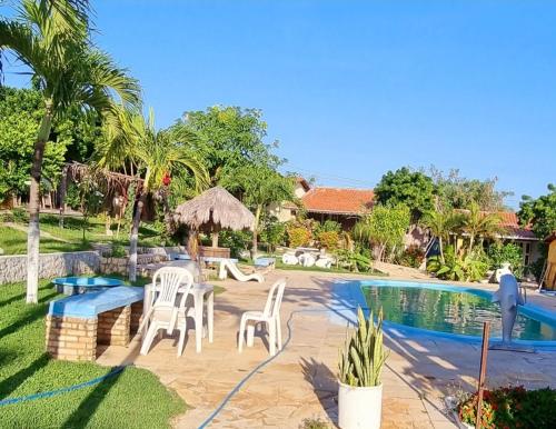 un patio trasero con piscina y sillas blancas en Casa no Residencia Familia en Canoa Quebrada
