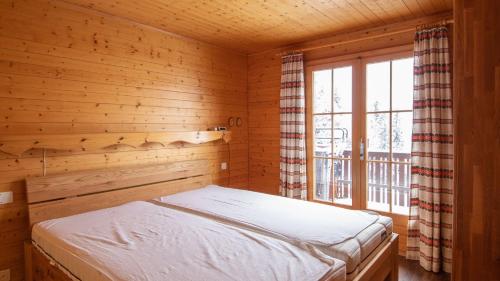 a bed in a wooden room with a window at Toggi EG in Bettmeralp