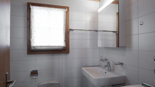 ein weißes Badezimmer mit einem Waschbecken und einem Spiegel in der Unterkunft Toggi OG in Bettmeralp