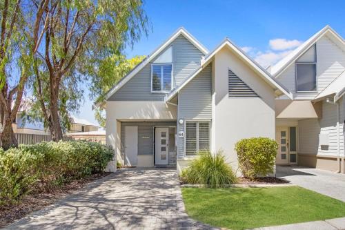 a white house with trees and a driveway at Escape to 64 at Cape View Resort in Busselton