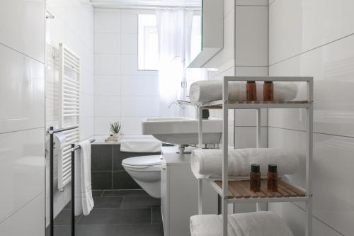 La salle de bains blanche est pourvue de toilettes et d'un lavabo. dans l'établissement Spirit Apartments Zentral mit gratis Parkplatz, à Lucerne