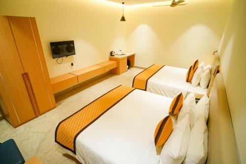 a hotel room with two beds and a tv at Hotel Nakshathra- A Royal Stay in Palani