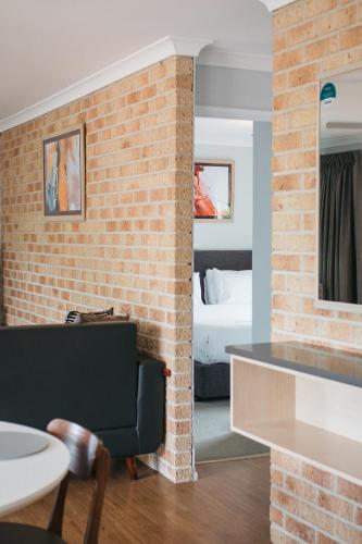 a room with a brick wall and a bedroom at Quality Apartments Banksia Albany in Albany