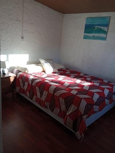 a bedroom with a bed with a red and white blanket at Tákate DoS in La Paloma