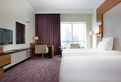 a hotel room with two beds and a flat screen tv at Pullman Dubai Jumeirah Lakes Towers in Dubai