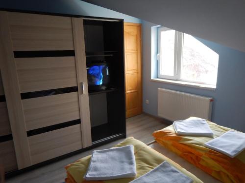 a bedroom with two beds and a cabinet with a television at Sissy Vendégház in Mórahalom