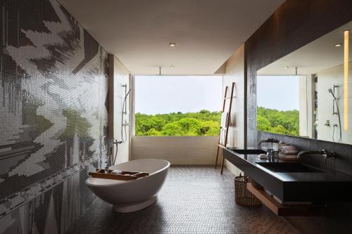 a bathroom with a tub and a sink and a window at Renaissance Bali Uluwatu Resort & Spa in Uluwatu