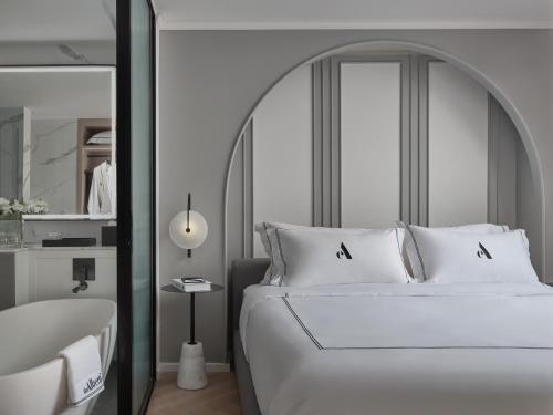 a bedroom with a large white bed and a tub at The Alberti Hotel - Sukhumvit 31 in Bangkok