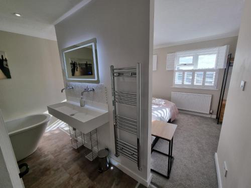 uma casa de banho com um lavatório, uma banheira e uma cama em 11 The Strand in the heart of Rye em Rye