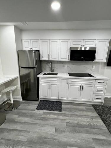 a kitchen with white cabinets and a stainless steel refrigerator at New Luxurious Studio Apartment in Brampton