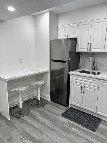 a kitchen with white cabinets and a stainless steel refrigerator at New Luxurious Studio Apartment in Brampton