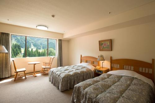 富山市にある立山国際ホテルのベッド2台と窓が備わるホテルルームです。