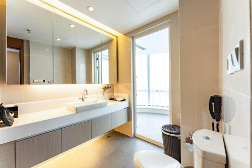 a bathroom with a sink and a mirror at Modena by Fraser Zhuankou Wuhan in Wuhan