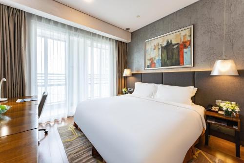 a hotel room with a large bed and a window at Modena by Fraser Zhuankou Wuhan in Wuhan
