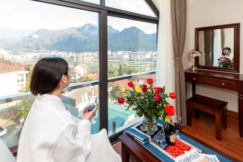 a woman looking out the window of a hotel room at Sapa Passion Hotel & Spa in Sa Pa