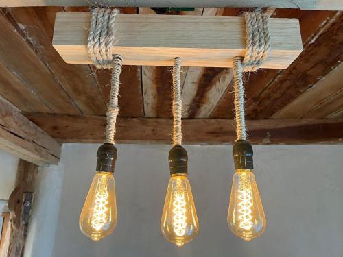 Trois lumières sont suspendues à un plafond avec des câbles dans l'établissement Xa am Natural Lodgement, à El Cuyo