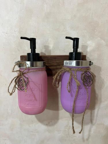 two pink bottles are hanging on a wall at Xa am Natural Lodgement in El Cuyo