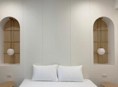 Moon House BKK Room 3A في بانغنا: غرفة نوم بيضاء مع نافذتين وسرير بمخدات بيضاء