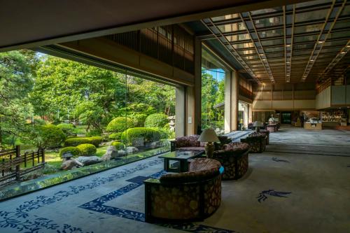 a lobby with tables and chairs and a garden at Tokiwa Hotel in Kofu
