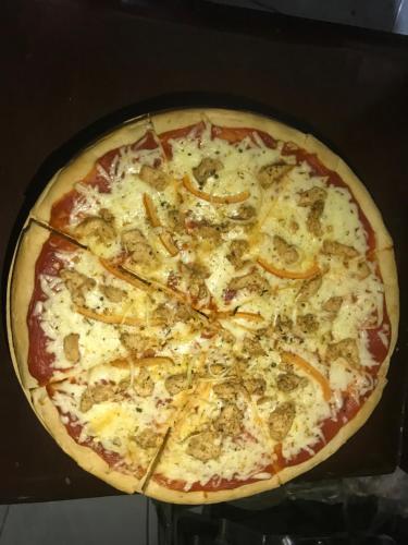 a pizza with cheese and toppings on a table at Chekesh Casa in Siquijor