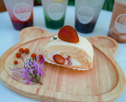 a piece of cake on a wooden cutting board with a strawberry on it at Heaven Hill Camping in Ban Thung Na