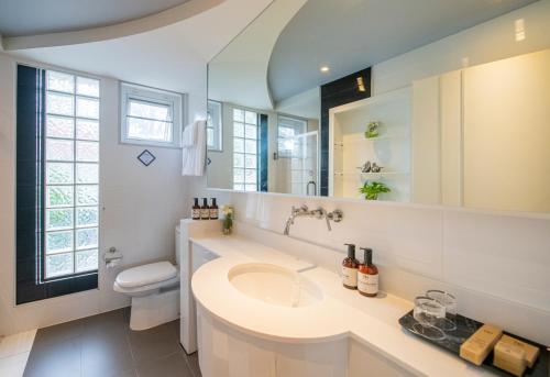 Un baño con lavabo, inodoro y espejo. en NH Boat Lagoon Phuket Resort, en Phuket