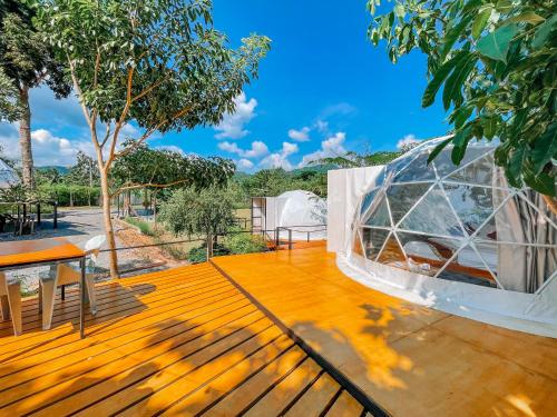 a glass house on a wooden deck with a table at Heaven Hill Camping in Ban Thung Na