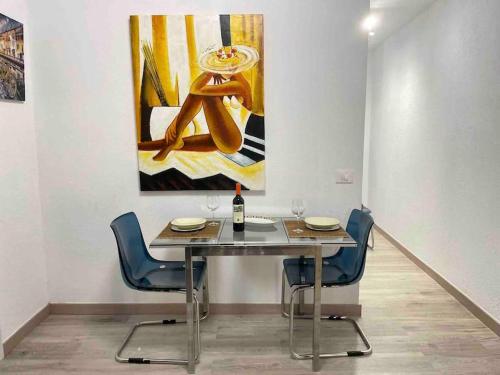 a dining table with two chairs and a painting on the wall at 2 Bedrooms Flat 50 mts away from Las Canteras beach in Las Palmas de Gran Canaria