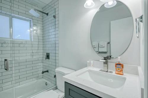 a white bathroom with a sink and a mirror at Blue Cove in Deerfield Beach