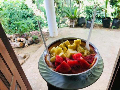 a bowl of fruit on a plate with two utensils at Green Horizon Ella in Ella