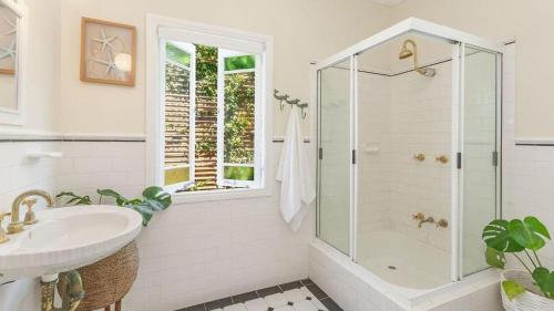 a white bathroom with a shower and a sink at Laze Daze in Yamba